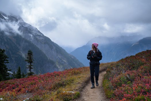 A woman hiker on a scenic trail in Washington, surrounded by vibrant fall colors and misty mountains.