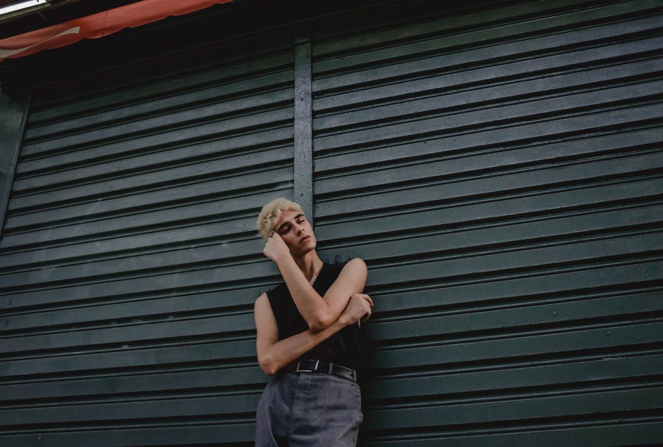 Fashionable blond model posing casually against a roller shutter.