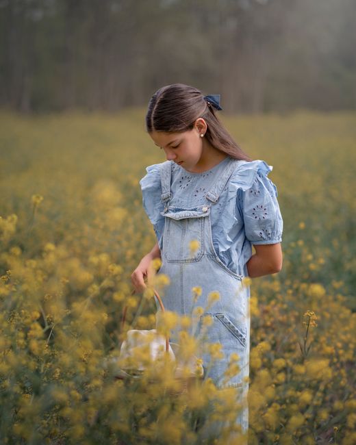 Young girl in denim surrounded by yellow flowers on a spring day.