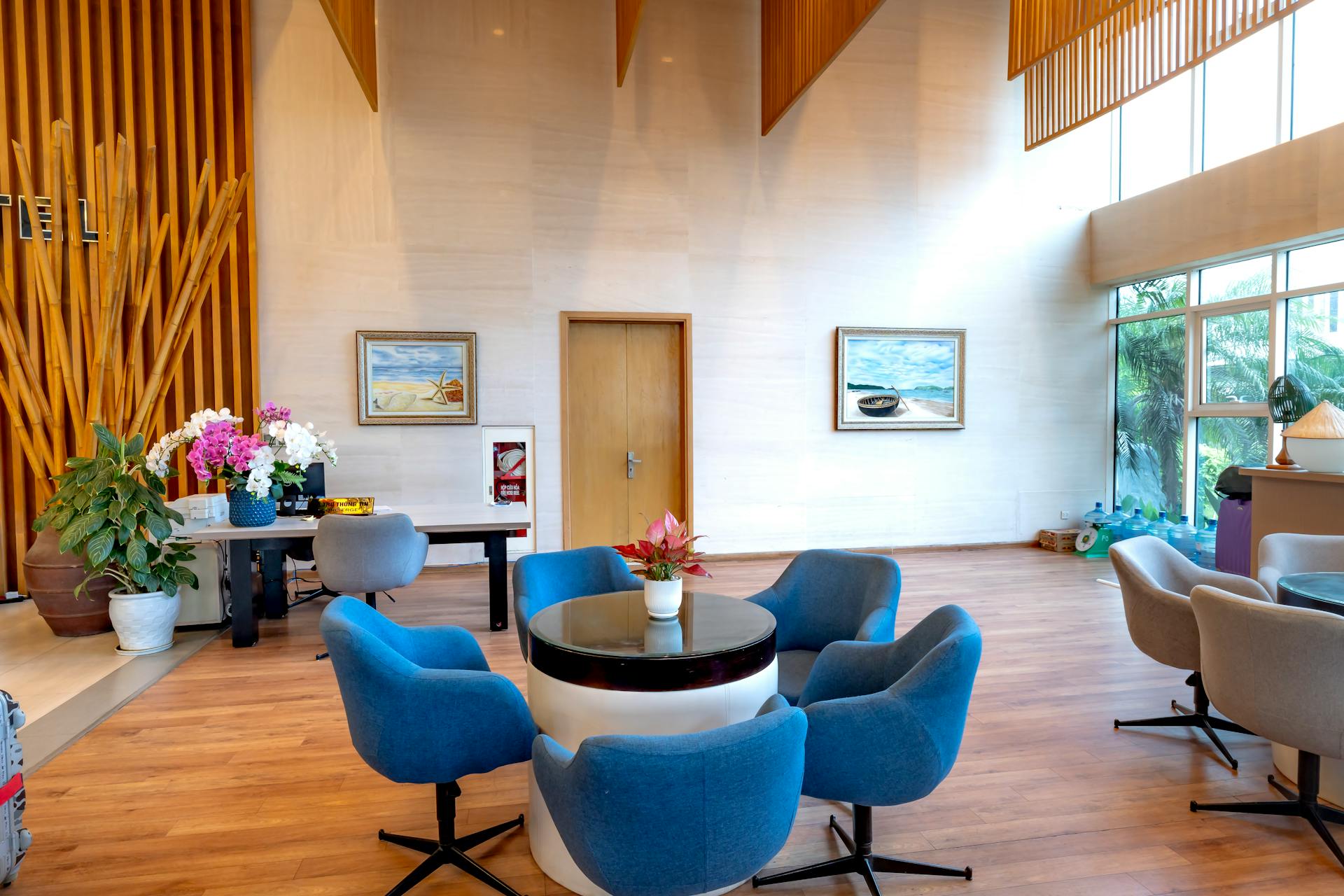 Spacious hotel lobby featuring modern decor, blue chairs, and natural light.