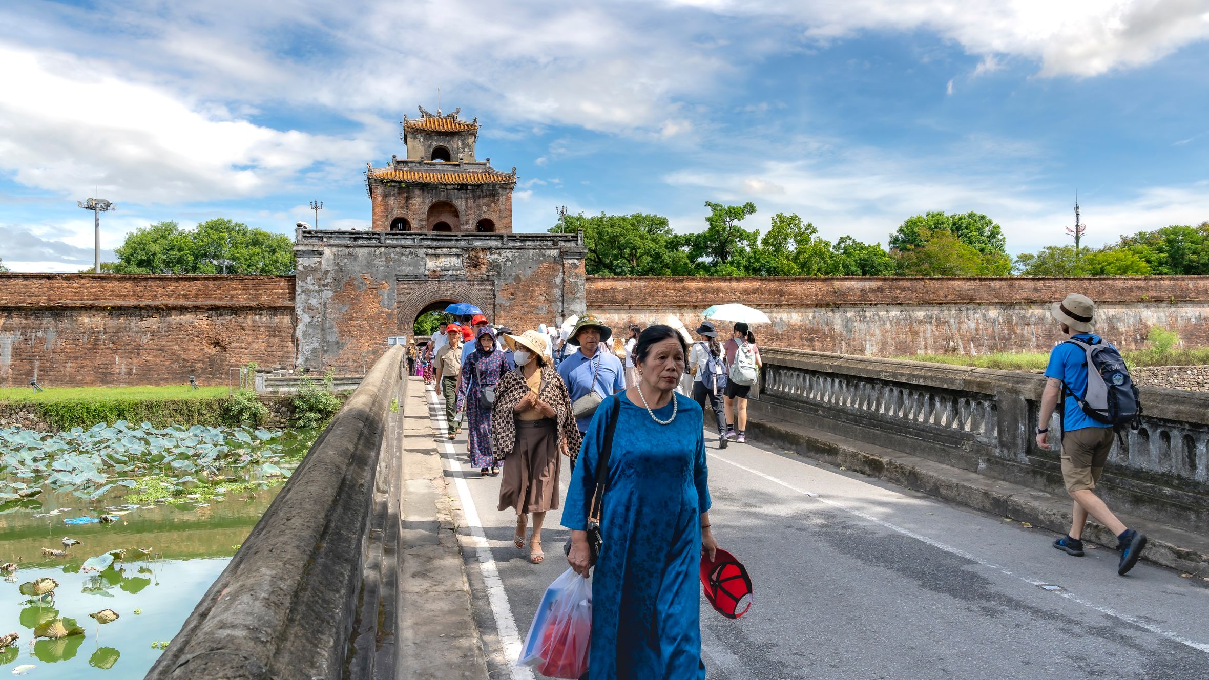 Tourists crossing the bridge at the Imperial Citadel in Hue, Vietnam, on a sunny day.