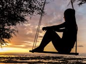 Silhouette of Woman on Swing during Golden Hour