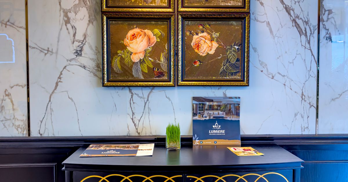 Chic interior featuring floral paintings, a dark elegant cabinet, and marble wall.
