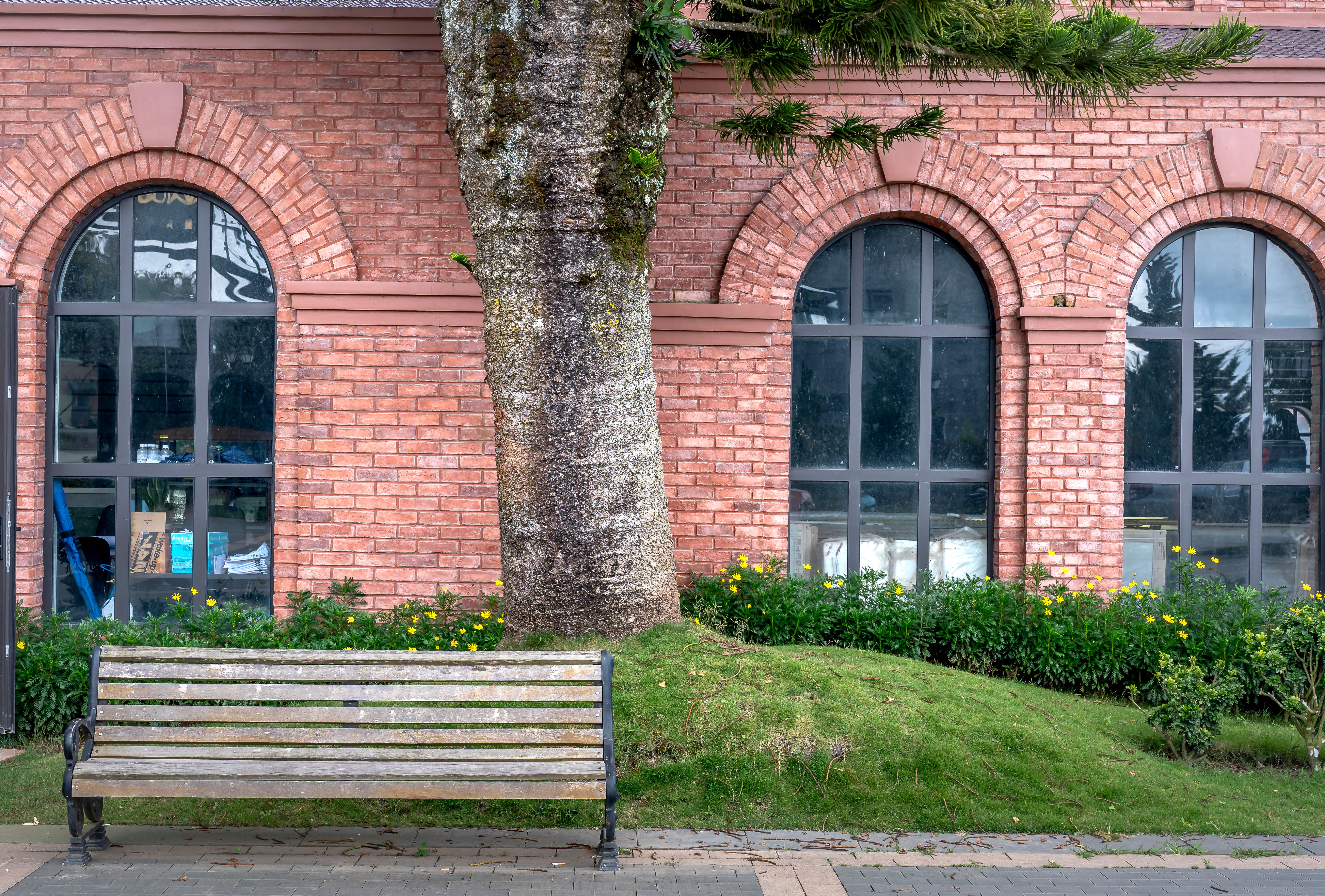 Scenic view of a rustic brick building with an inviting bench and lush garden.