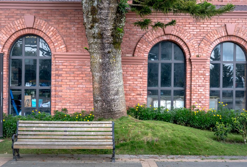 Scenic view of a rustic brick building with an inviting bench and lush garden.
