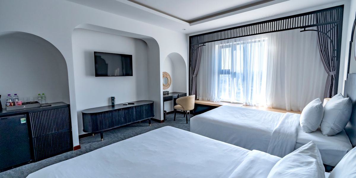 Modern hotel room with two beds and natural light from a large window