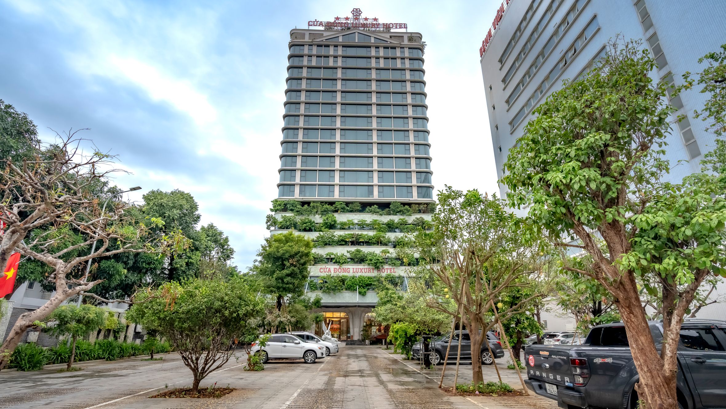 A modern luxury hotel with greenery in a bustling city environment.