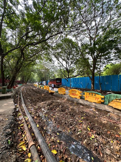 Free Busy construction site with fencing, machinery, and trees in Mumbai, India Stock Photo