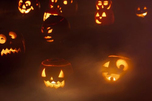 Free Creepy jack-o'-lanterns glowing in thick fog, creating an eerie Halloween night ambiance. Stock Photo