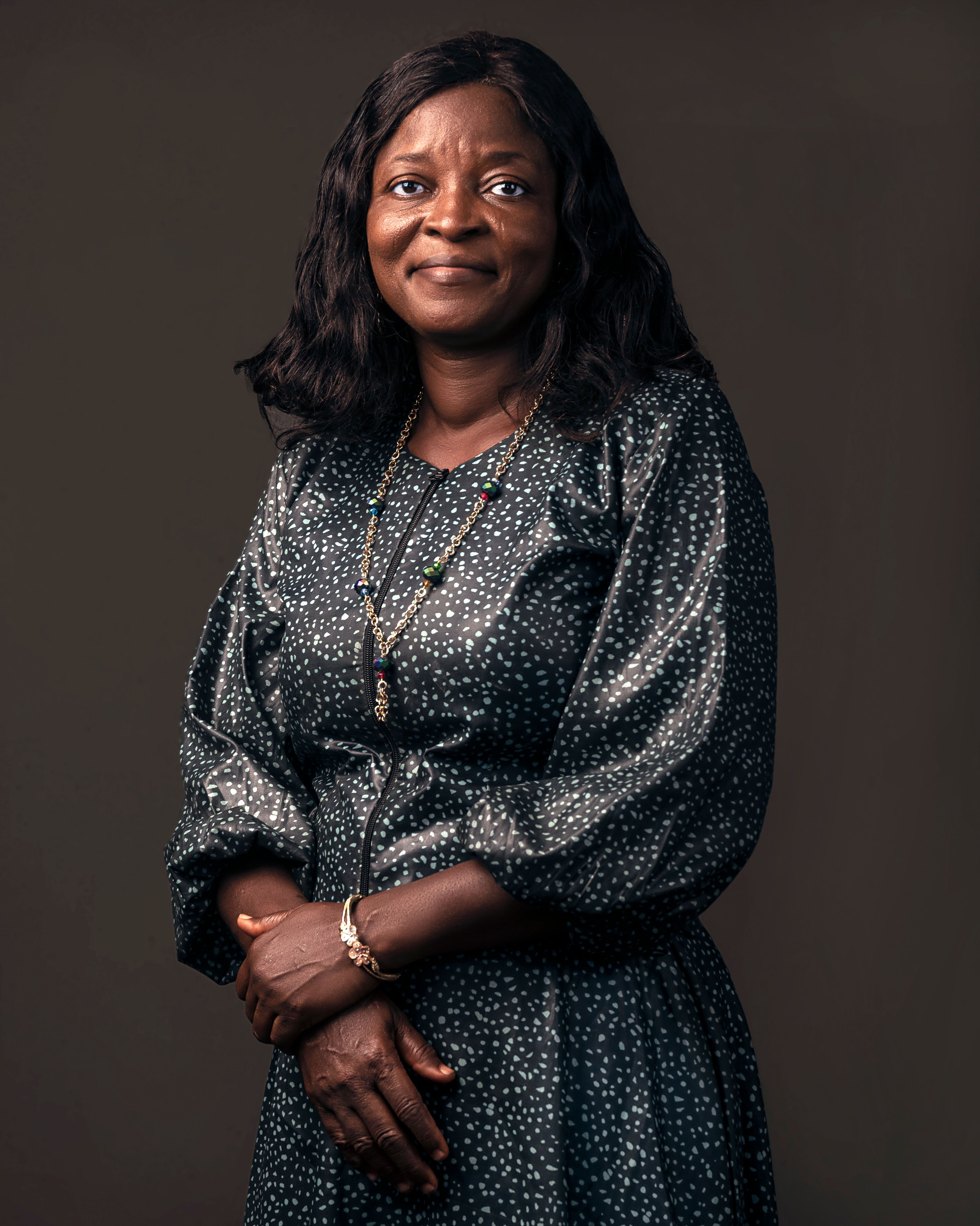 Portrait of an adult woman smiling confidently in a stylish patterned dress against a subtle background.