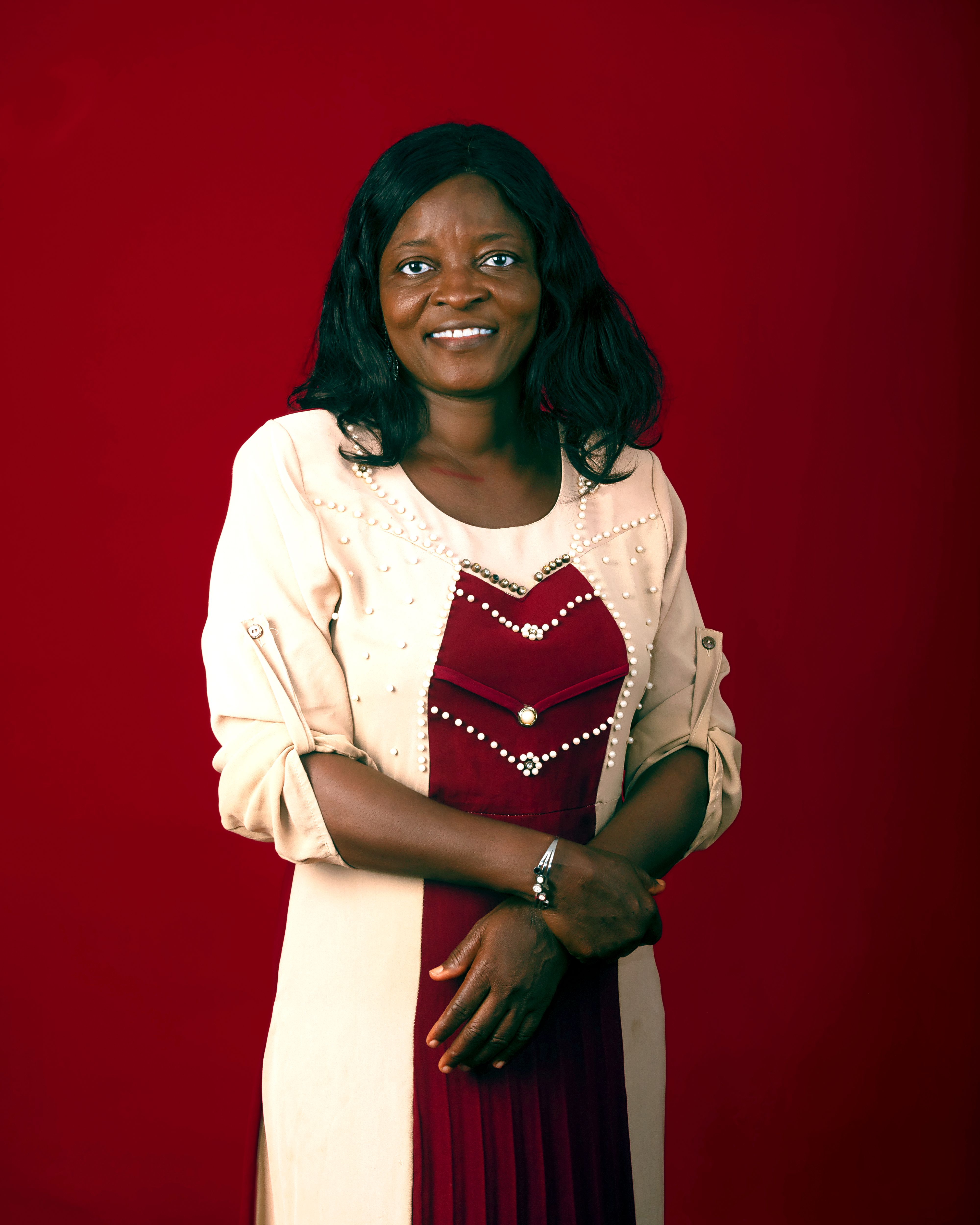 Woman in elegant attire smiling in front of a red backdrop.