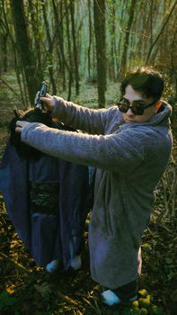 Man collecting trash in forest with garbage bag, promoting environmental awareness.