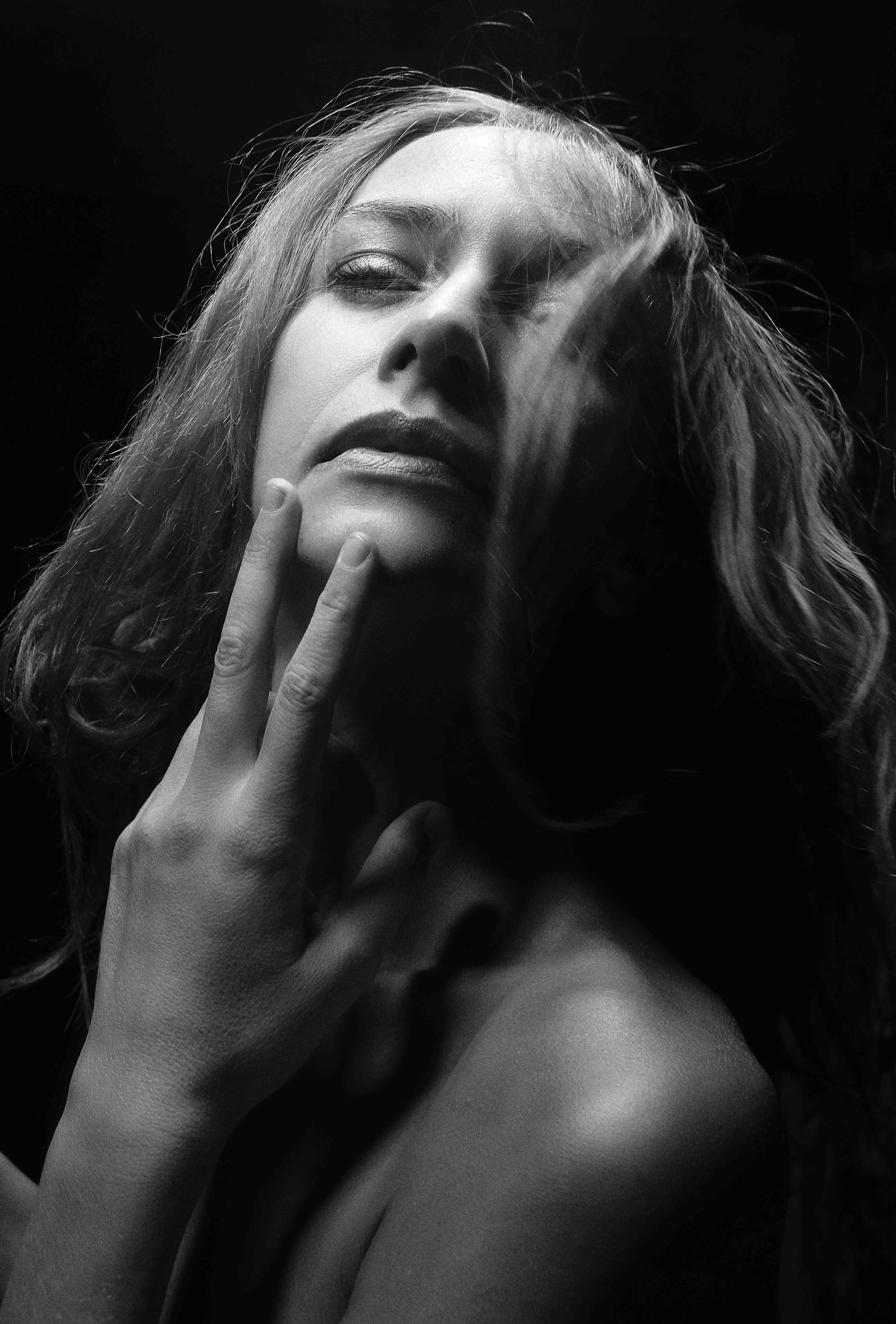Striking black and white portrait of a woman with dramatic lighting, showcasing emotion and elegance.