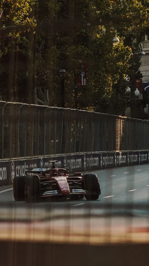 Free Formula 1 race car speeds through a scenic urban track surrounded by trees and buildings. Stock Photo