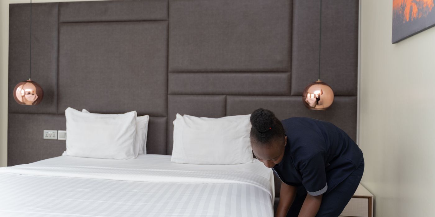 Hotel staff member making a bed in a modern hotel room