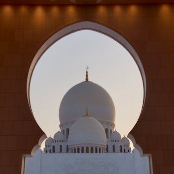 A captivating view of the Sheikh Zayed Grand Mosque's dome framed by an ornate arch in Abu Dhabi.