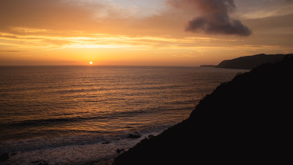 Goldener Sonnenuntergang über dem Meer von einer Küstenklippe aus