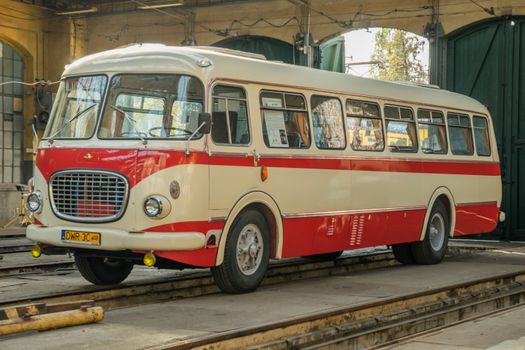 A classic red and white vintage bus parked inside a Wrocław tram garage.
