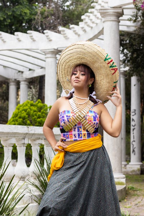 Free Young woman wearing traditional Mexican attire in an outdoor cultural space. Stock Photo