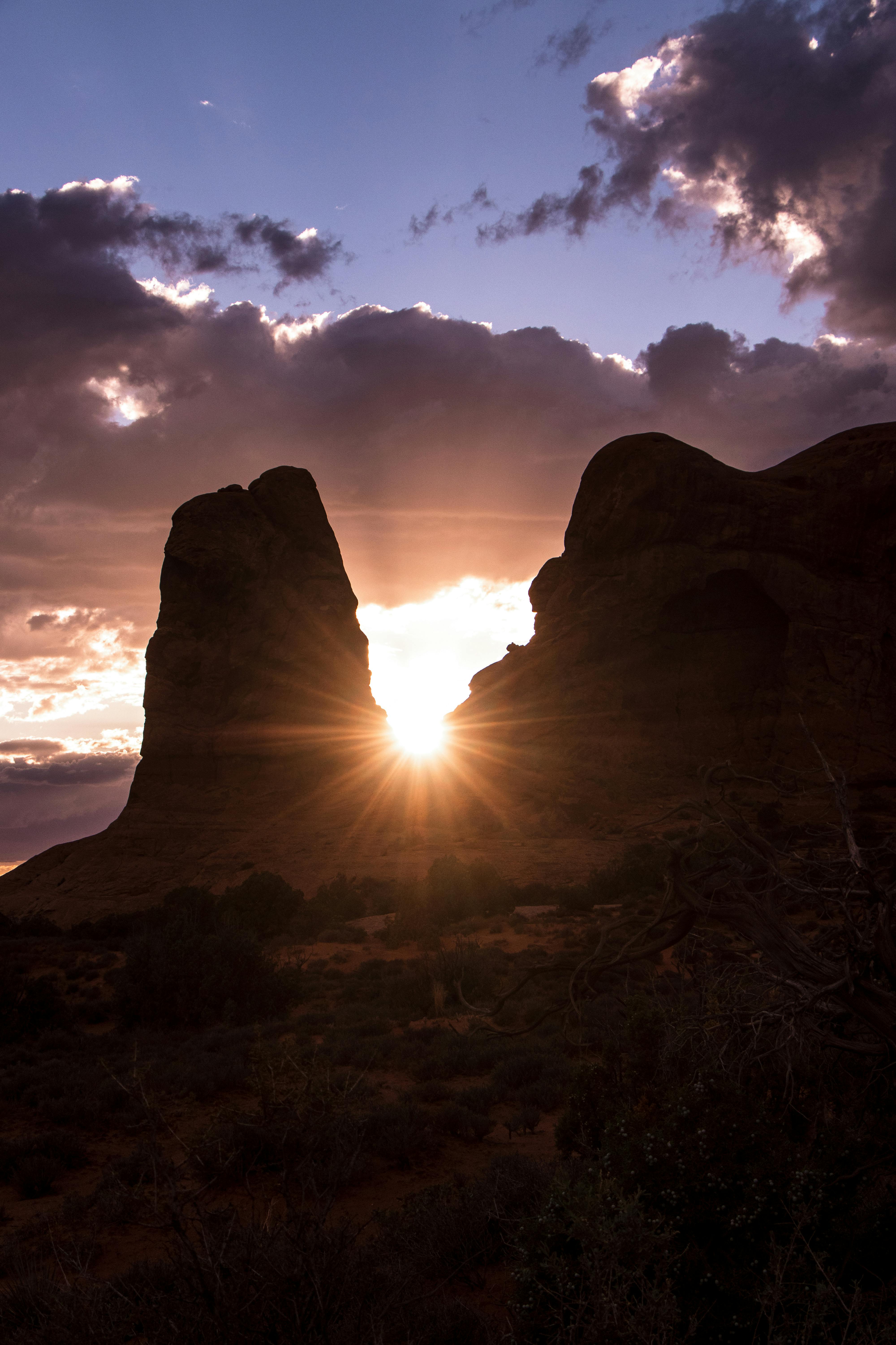 Sunset over a dramatic canyon landscape, highlighting rocky formations and glowing skies.