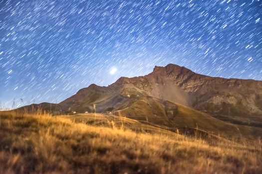 Beautiful star trails illuminate the night sky over a serene alpine landscape in France.