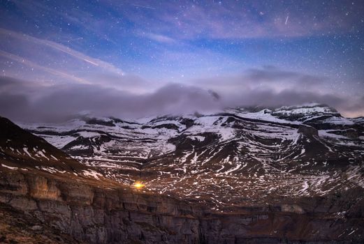 Stunning night view of snowy peaks in Ordesa Valley, Spain under a galaxy filled sky.