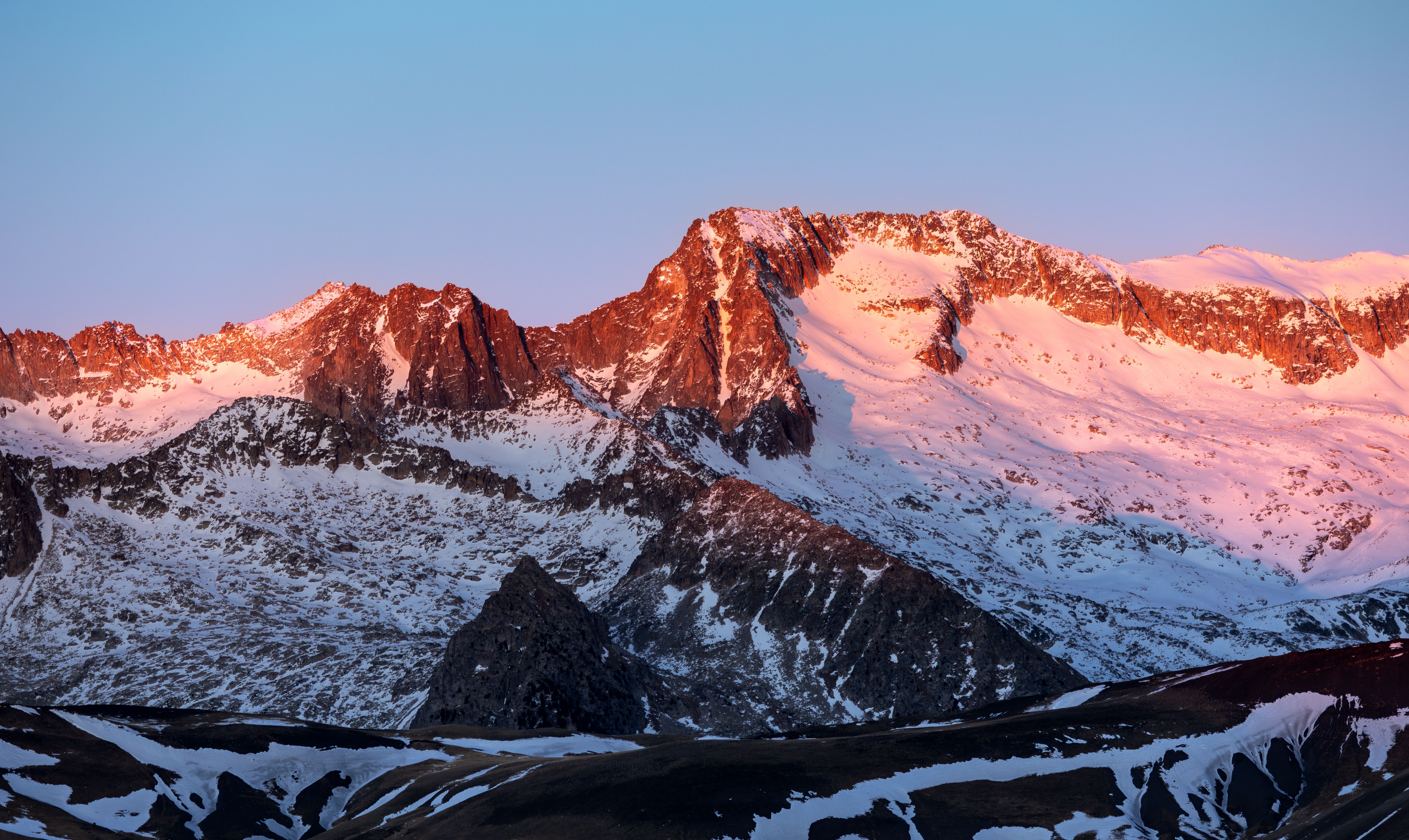 Low sun on the snow-covered peaks of a mountain range at dusk
