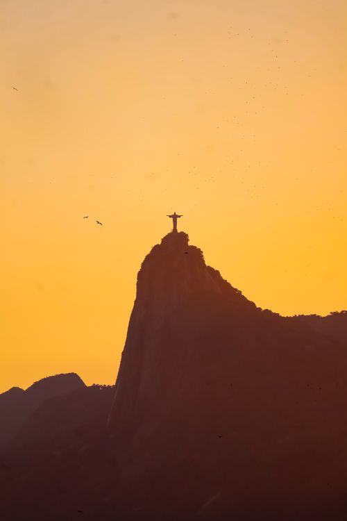 Free Silhouette of Christ the Redeemer statue against a golden sunset in Rio de Janeiro, Brazil. Stock Photo