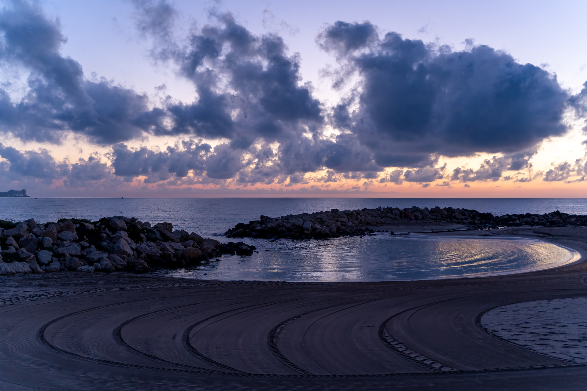 Peaceful sunrise over Comunidad Valenciana beach with rocks and calm water.