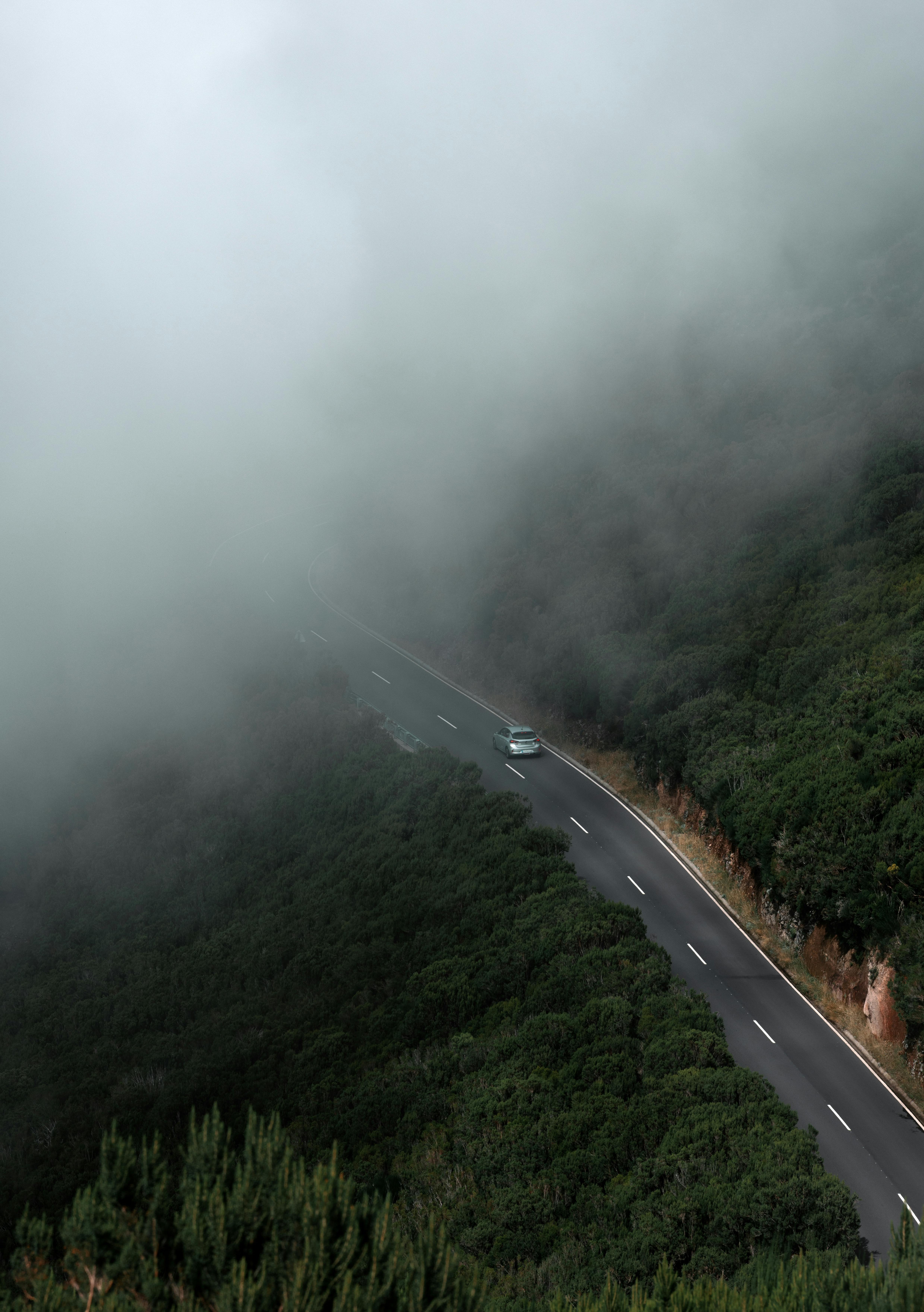 Aerial view of a winding road through dense fog in Madeira, Portugal.