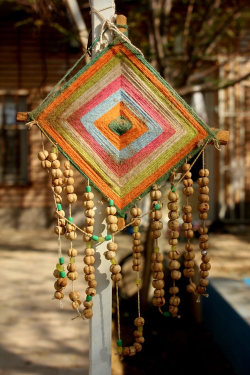 Free Vibrant handmade string art with beads hanging outside on a sunny day. Stock Photo