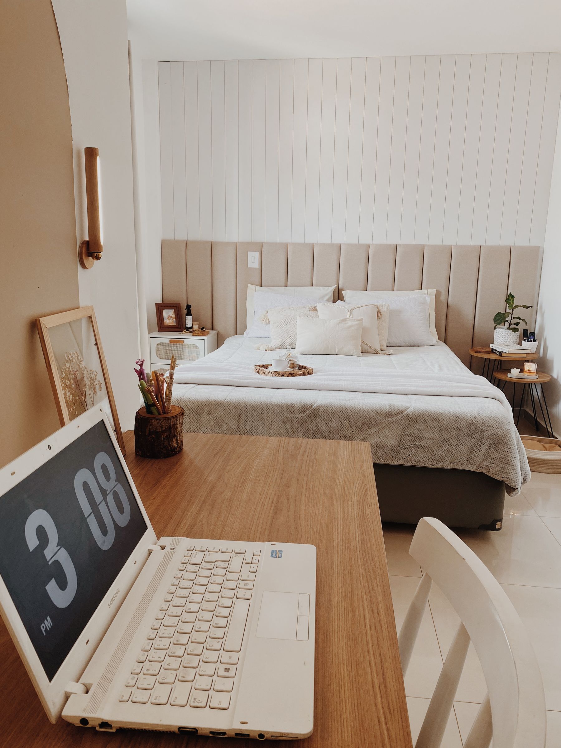 Neutral bedroom workspace with a timber desk, chair, lamp and storage