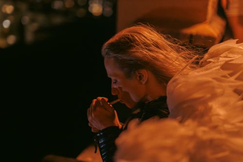 Free Pensive person smoking at night against a blurred city background. Stock Photo