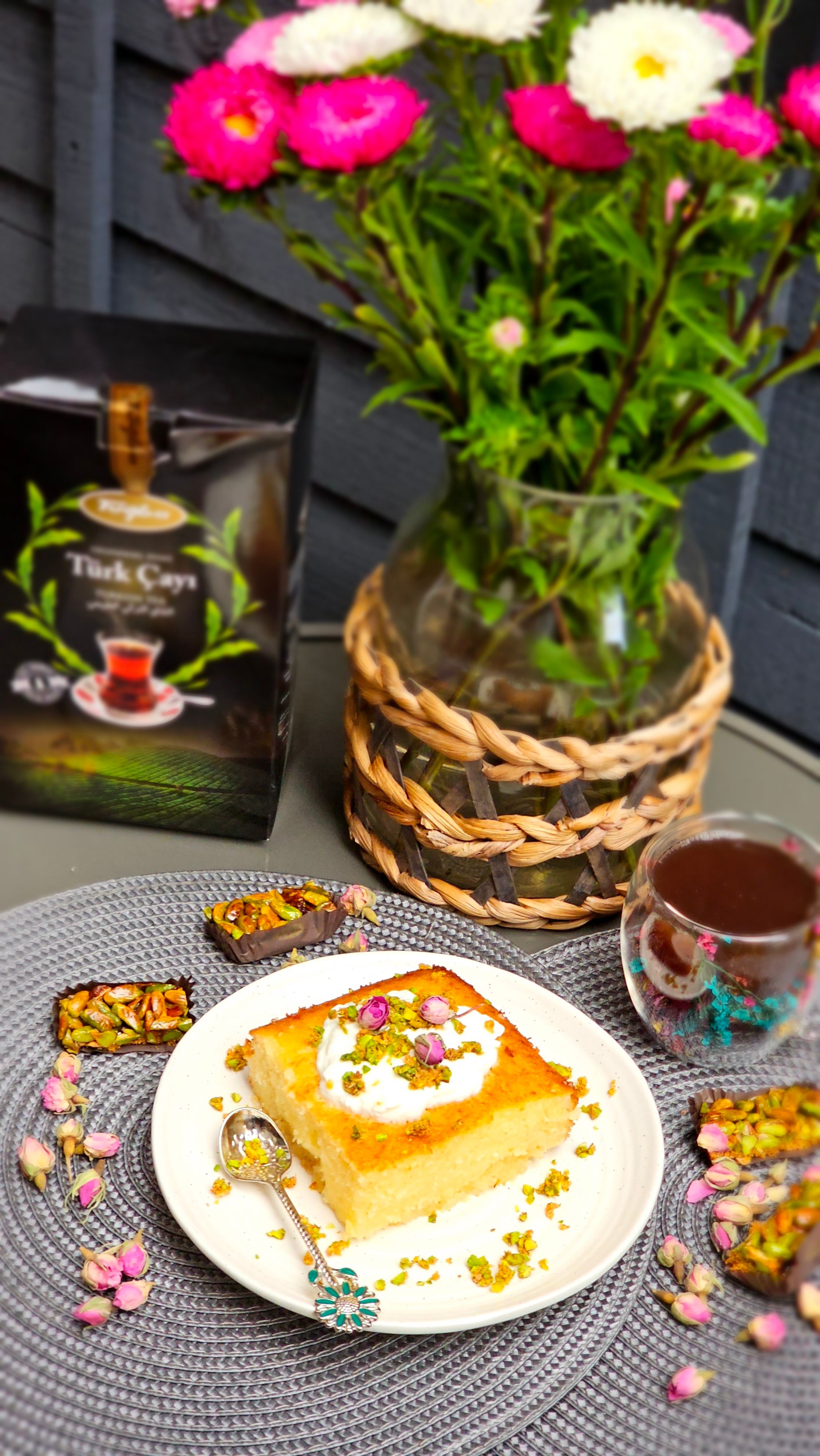 Revani dessert served with Turkish tea, garnished with pistachios and flowers.