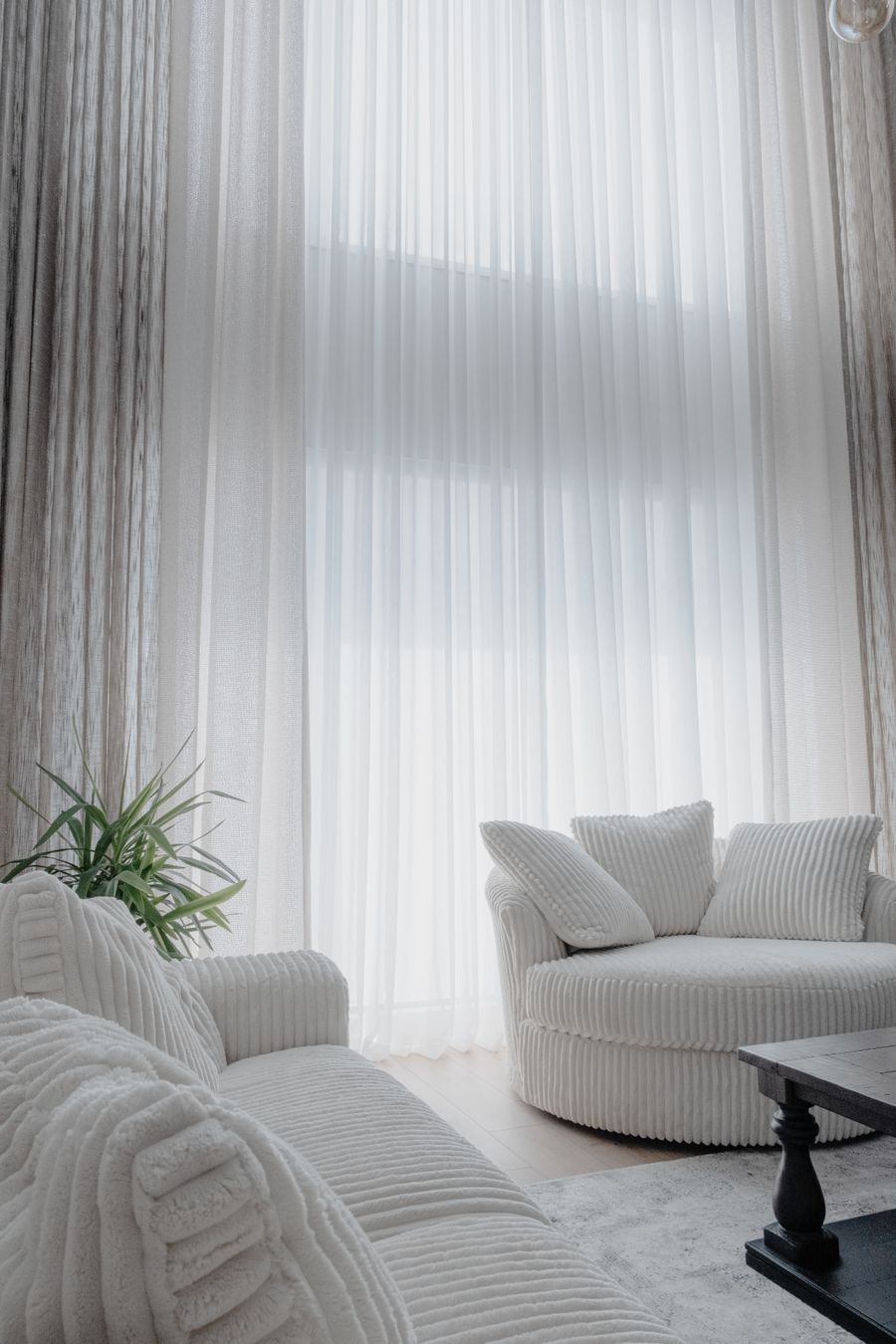 Sala clara com sofá, cortinas e decoração em tons neutros