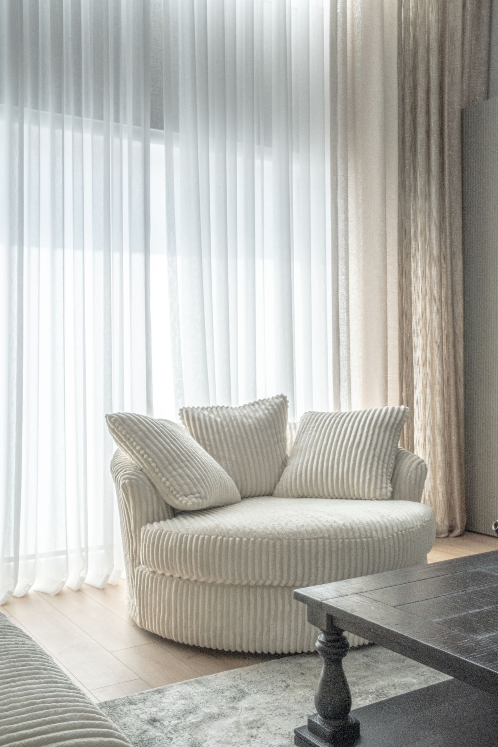 Round swivel accent chair in a bright, sunlit studio apartment living room