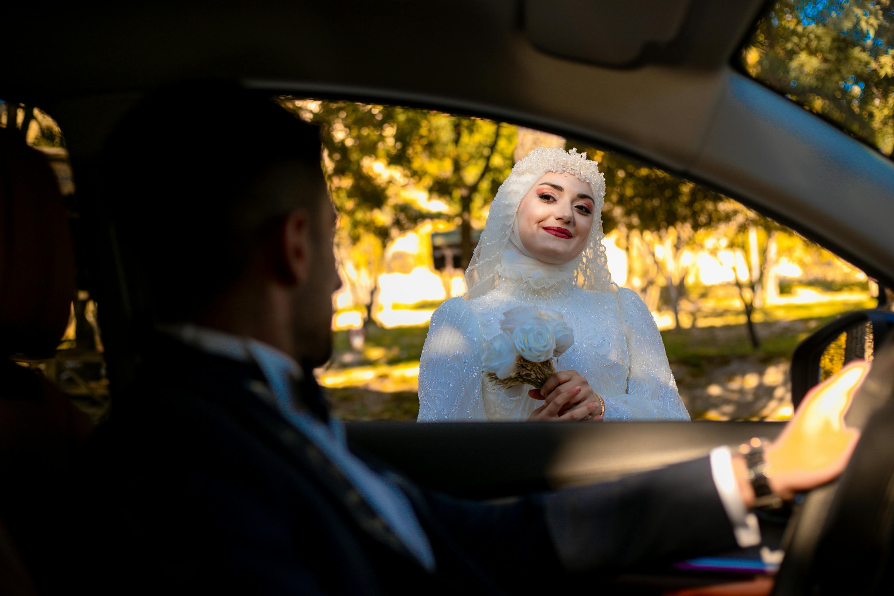 Tesettürlü gelin adayı prova yaparken: aynada gelinlik deneme, butik mağaza ortamı, profesyonel danışman, fitting room