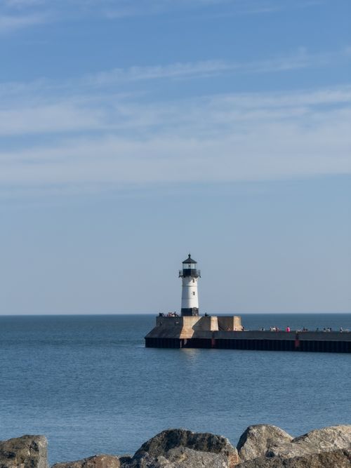 Free Scenic view of a lighthouse on Lake Superior with blue skies and calm waters in Duluth, Minnesota. Stock Photo