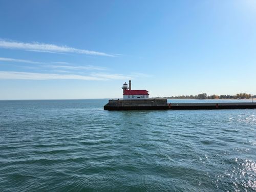 Free A picturesque lighthouse on the coast under clear blue skies and sunlight. Stock Photo