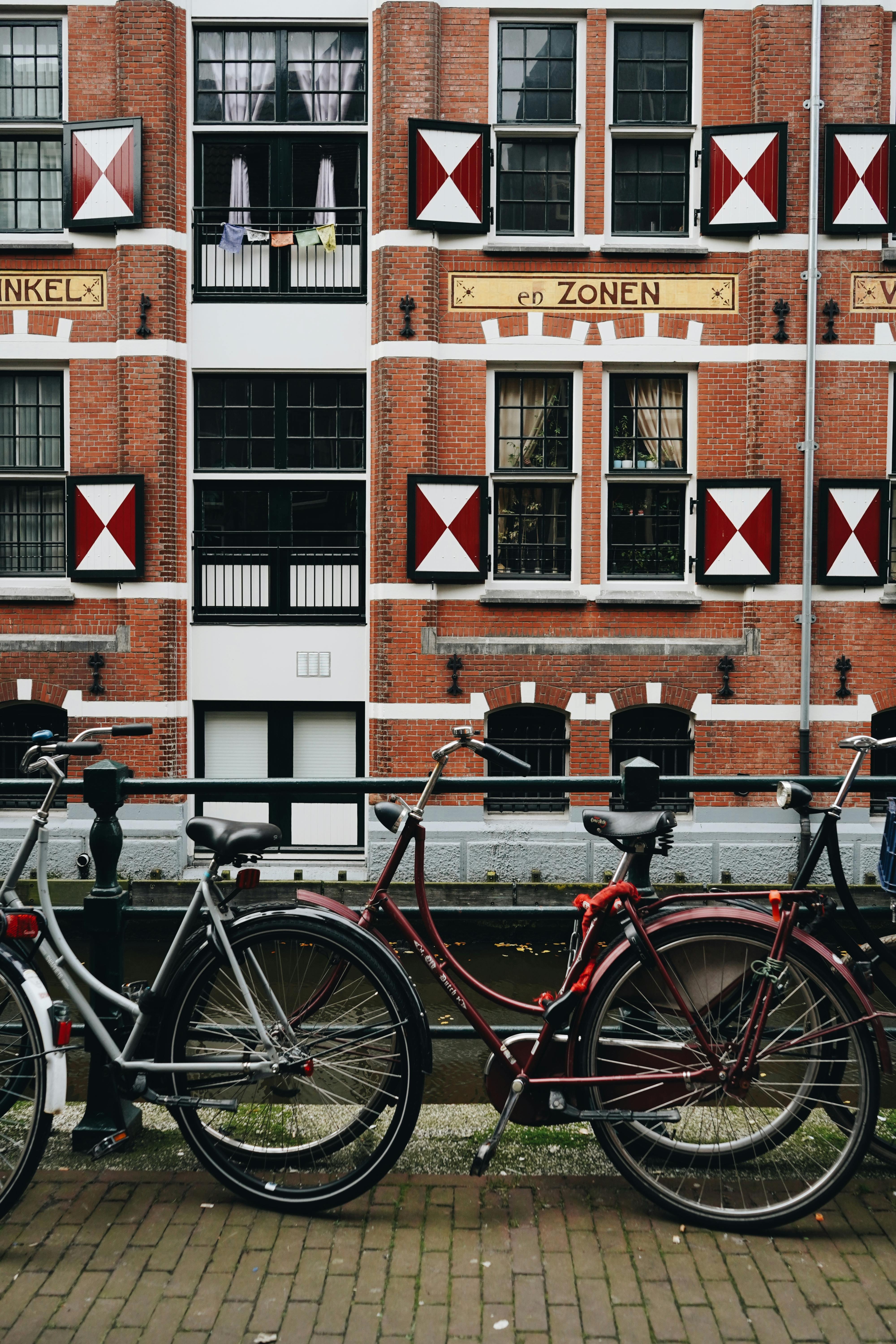 Colorful bicycles parked by a canal in front of a historic Dutch building.