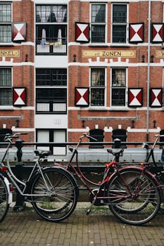 Colorful bicycles parked by a canal in front of a historic Dutch building.