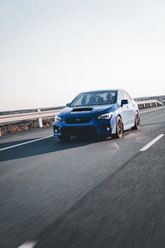 Dynamic shot of a blue car speeding along a clear highway in daylight.