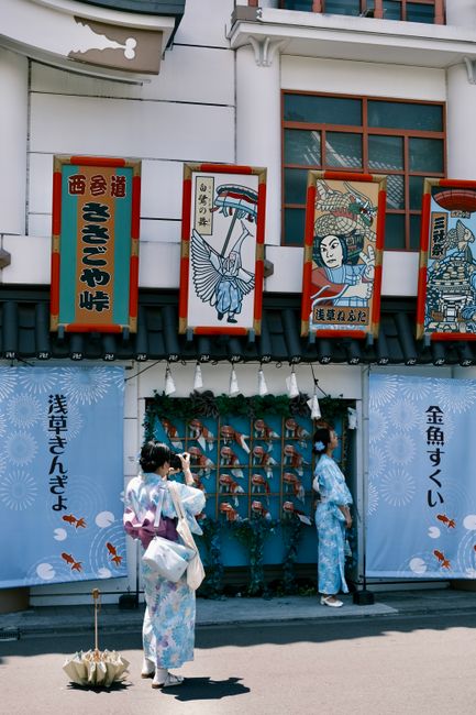 Two women in kimonos admire traditional art in Asakusa, Tokyo, Japan.