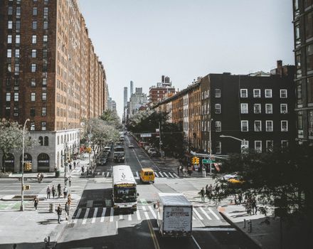Vibrant cityscape of New York City street with vehicles and pedestrians on a sunny day.
