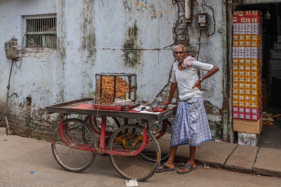 An elderly vendor selling street snacks in Mathura, India.