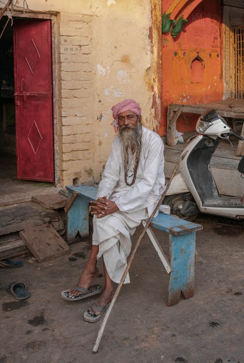 Free Elderly man with white beard in traditional attire sits outside in rural India Stock Photo