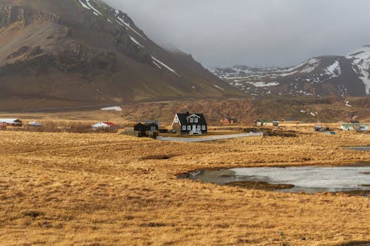 A serene landscape featuring an isolated black house amidst the rugged Icelandic terrain.