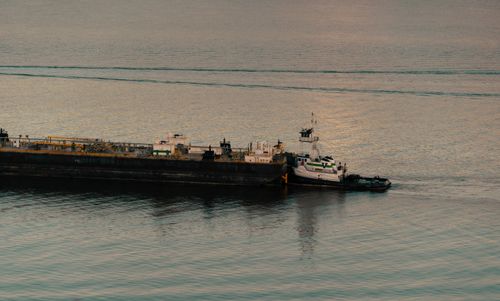 Free A tugboat expertly maneuvers an industrial barge across calm waters during daylight. Stock Photo