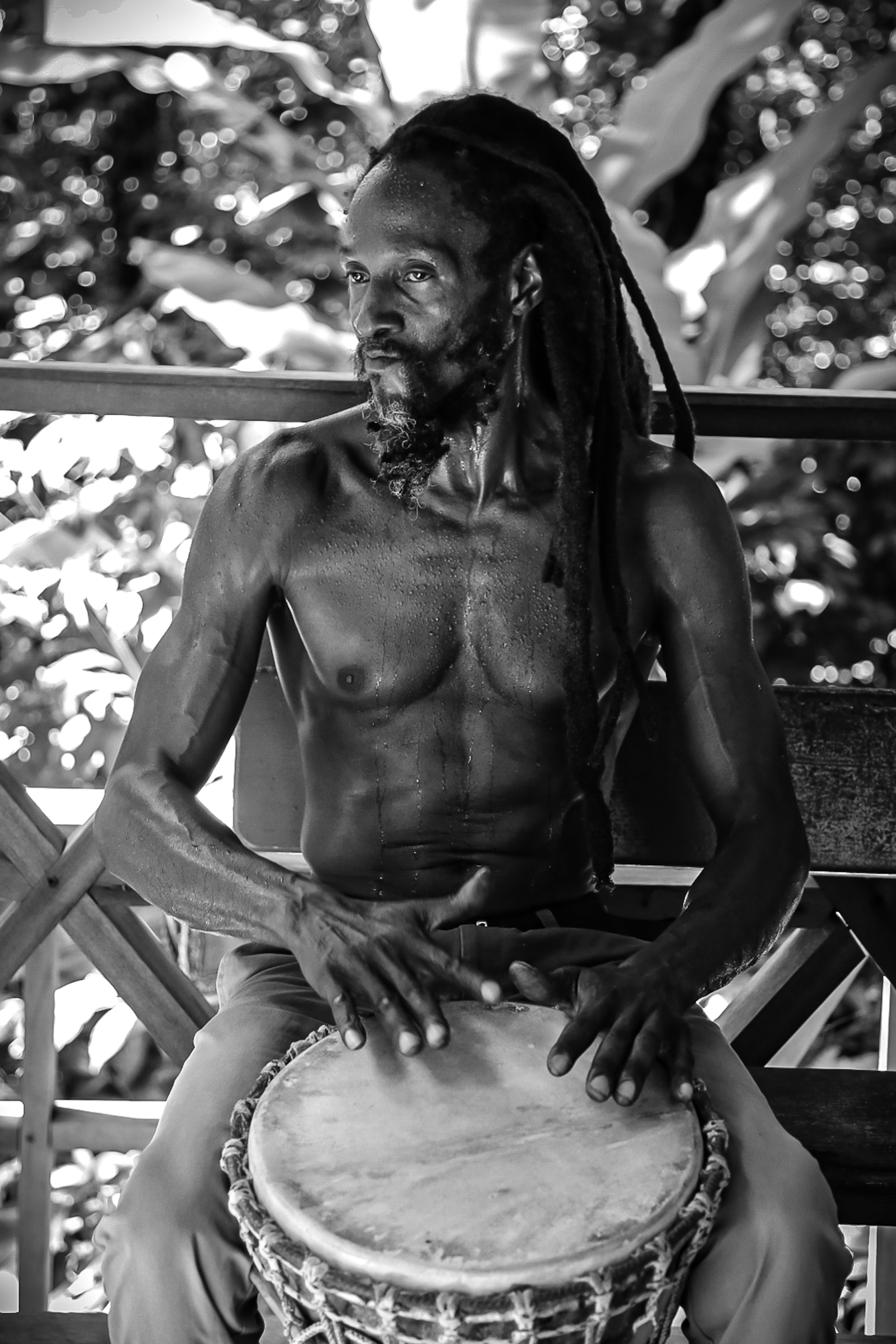 Intense black and white portrait of a man playing a djembe drum outdoors in Dominika.