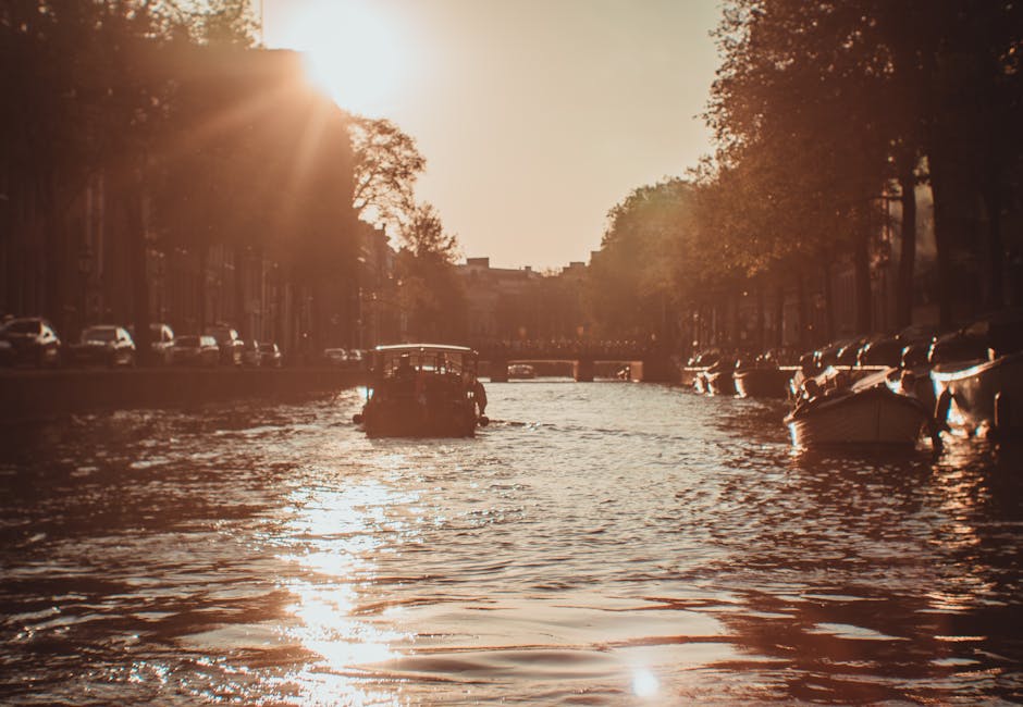 A tranquil boat ride in Amsterdam's iconic canal during a vibrant sunset, showcasing the city's charm.